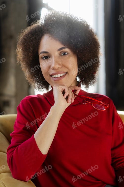 Preview: Smiling African American woman holding red eyeglasses looking at camera isolated on background
