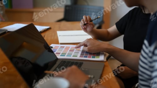 Preview: Team of designer working on a new project and choosing color from color palette at office desk.