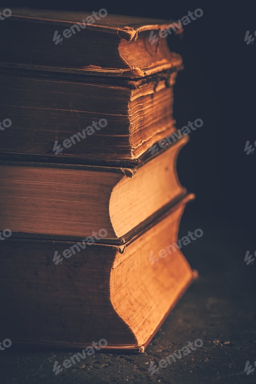 Preview: Stack of antique leather bound books against dark background