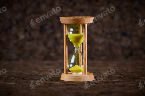 Preview: Sand running through the bulbs of an hourglass on a dark cork tree background.