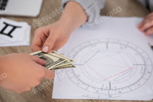 Preview: Cropped view of man paying to astrologer with natal chart on table