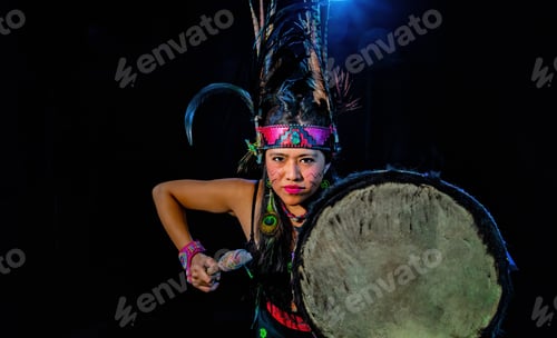 Preview: Young female with traditional dress dancing with trappings with feathers and drum