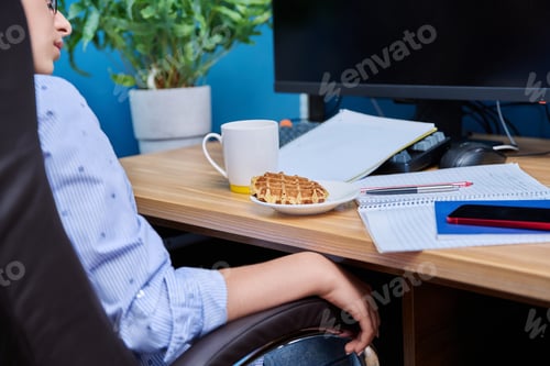 Preview: Female teenager sits at home at table studying, snacking on waffles, drinking tea