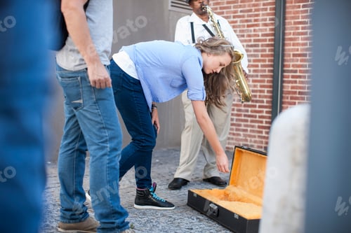 Preview: Pedestrian throwing money into street musician's music case