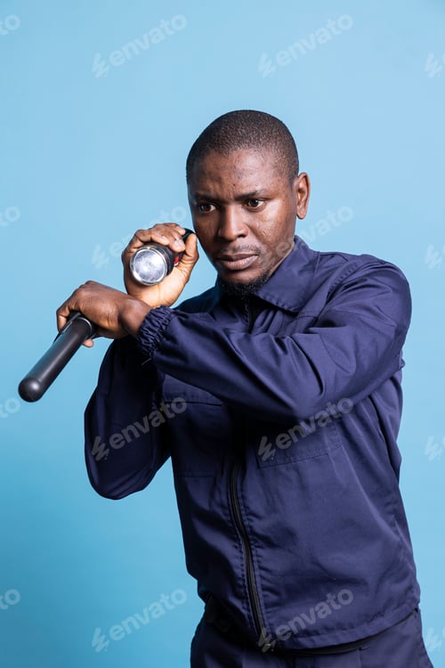 Preview: Trained security officer inspecting the premises with a flashlight and his baton