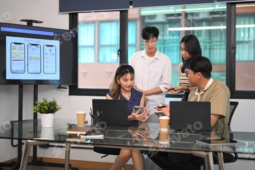 Preview: Group of young professionals discussing smartphone UI/UX wireframes during a creative meeting