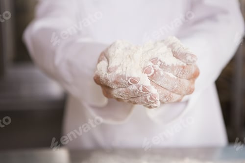 Preview: Close up of bakers hands holding flour in the kitchen of the bakery