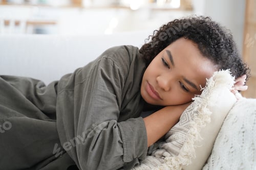 Preview: Tired upset african american teen girl lying on sofa at home alone. Teenage problems, fatigue