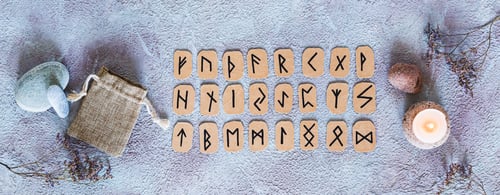 Preview: Scandinavian runes for fortune telling, pouch and candle on the table top view web banner