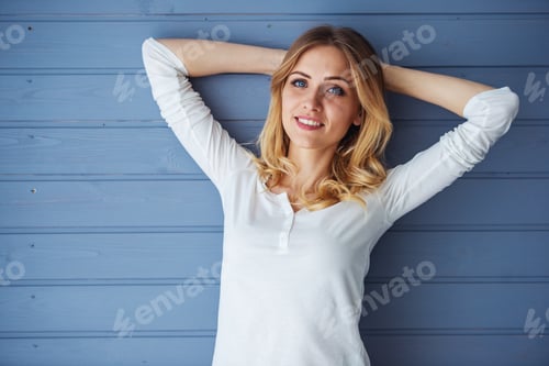 Preview: Smiling Blonde Woman Posing Against a Blue Wall