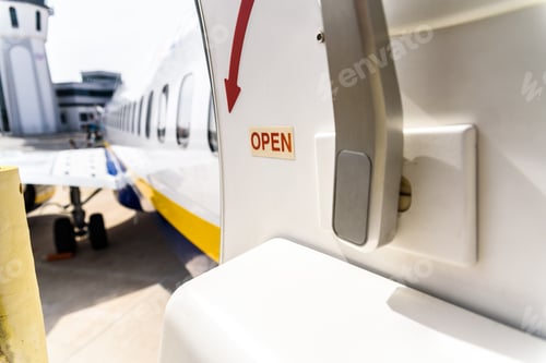 Preview: Open door of a plane parked while passengers disembark.