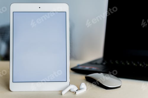 Preview: Tablet with whit screen next to a laptop on a desk - technology and business concept