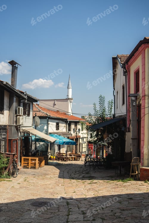 Preview: Stone road surrounded by buildings and cafes under sunlight and a blue sky