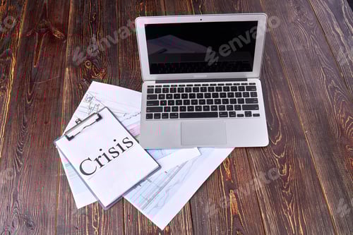 Preview: Top view laptop with clipboard with crisis word.