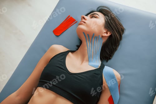 Preview: Top view. Woman with kinesio tape is in the clinic indoors