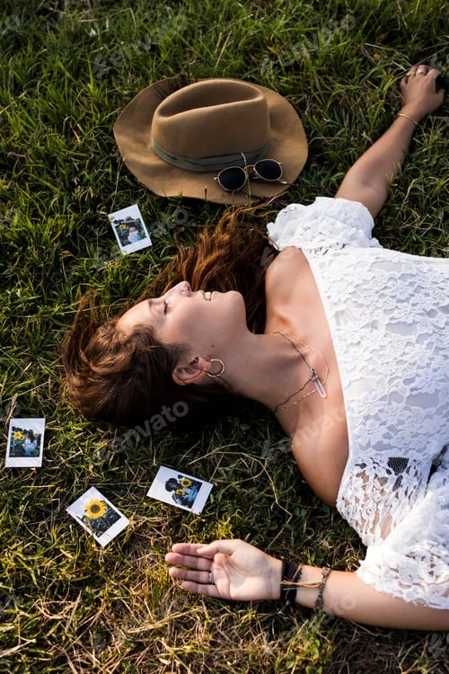 Preview: Happy woman lying in a field surrounded by instant photos