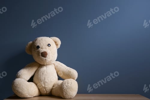 Preview: Abandoned teddy bear on table against dark background. Time to visit child psychologist