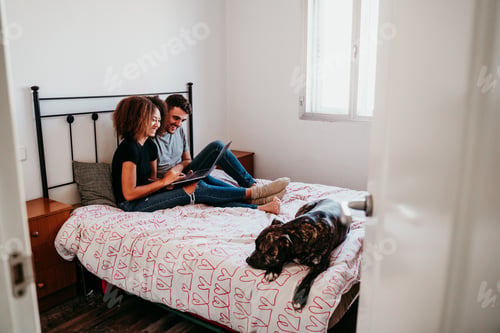 Visualização: casal interracial em casa com cachorro usando laptop.Mulher afro-americana e homem caucasiano. amor étnico