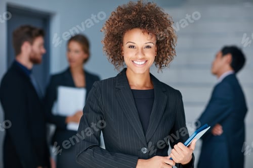 Preview: Portrait of a young businesswoman standing in an office with colleagues in the background
