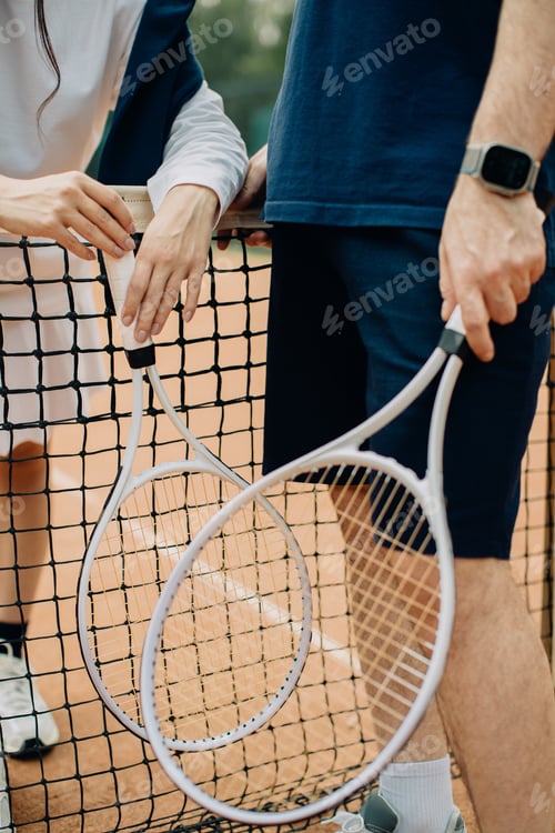 Preview: Tennis players holding rackets on court net
