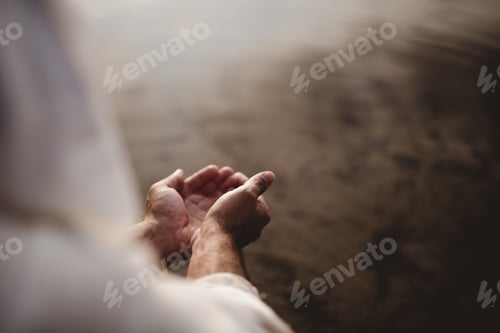 Preview: Beautiful shot of a male wearing a biblical robe holding water with his palms