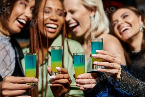 Preview: selective focus of shot glasses near cheerful multiethnic girlfriends on blurred background