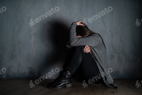 Preview: Sad mid-adult woman, alone in darkness, sitting and thinking