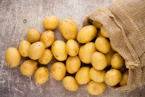 Preview: Sack of fresh raw potatoes on wooden background, top view.