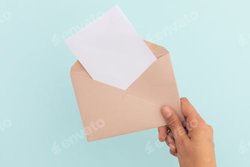 Preview: Hand of caucasian woman holding opened envelope with letter over pale blue background