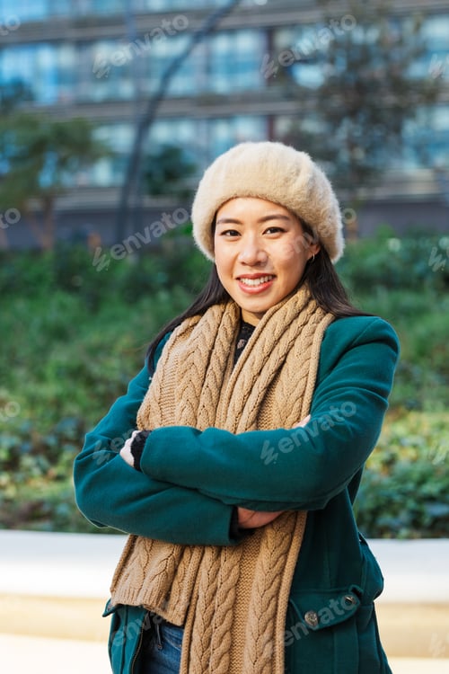 Preview: Asian business woman looking at camera and smile while posing with arms crossed outdoors on the