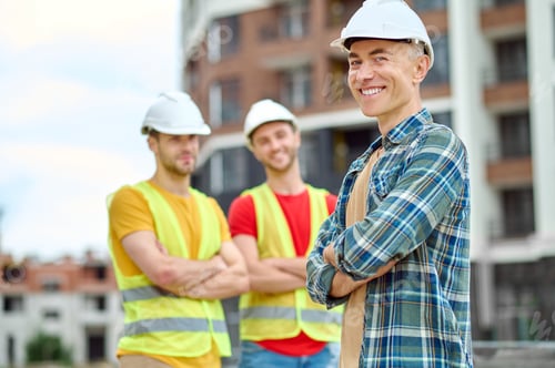 Preview: Man smiling at camera and workers behind