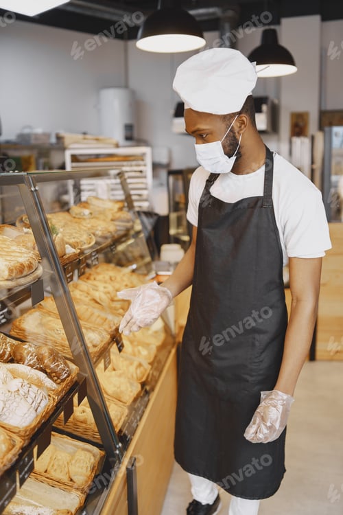Preview: Fine African American man in mask offering pastry