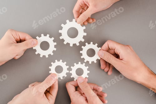 Preview: cropped view of people holding white gears on grey background