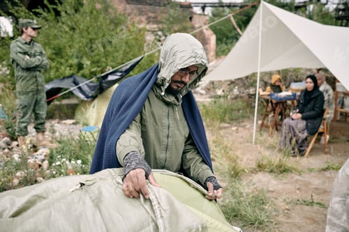 Preview: Refugee Man Covering Tent With Sack