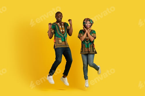 Preview: Thrilled african couple jumping up and gesturing on yellow