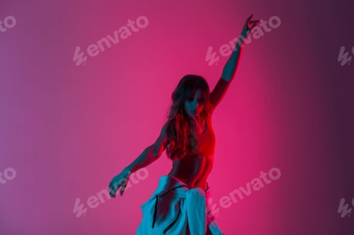Preview: Pretty dancer woman in stylish wear in trendy shoes dancing with colorful light. Sporty girl