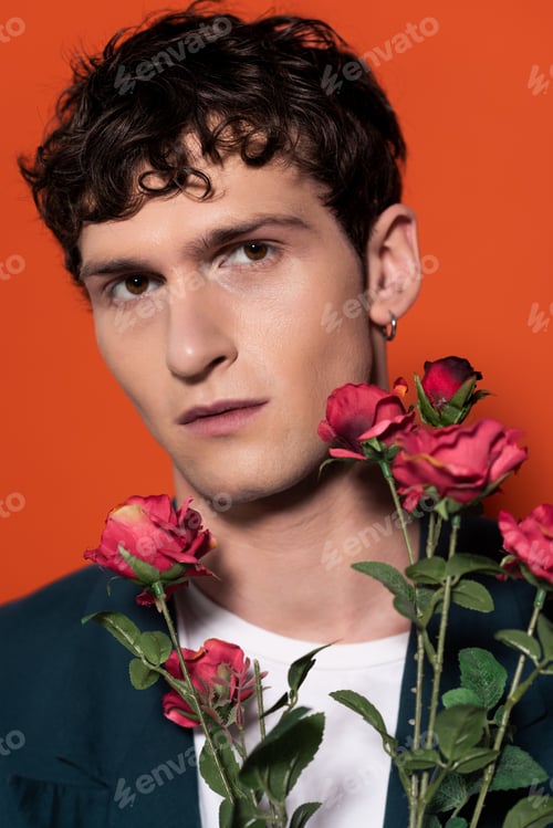 Preview: romantical young man posing near roses isolated on red