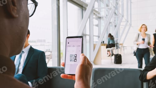 Preview: Male Passenger In Airport Departure Lounge Looking At Digital Boarding Pass On Smart Phone