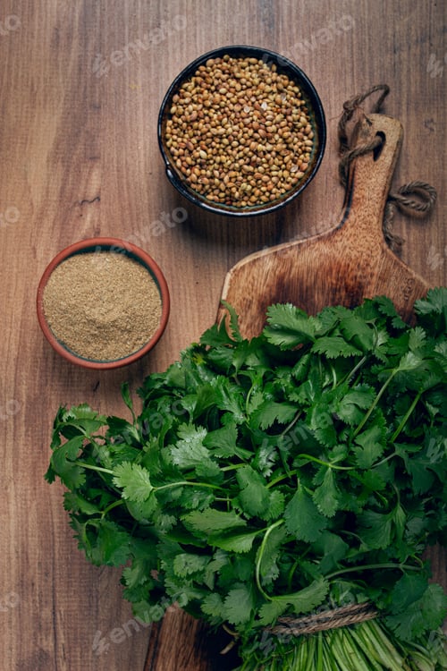 Preview: a bunch of fresh cilantro, coriander seeds and powder bowls, close-up, top view,