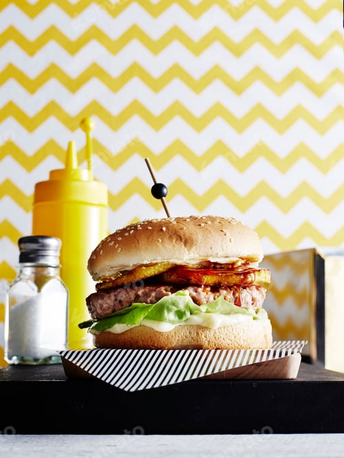 Preview: Cheeseburger with bacon and lettuce on a patterned background.