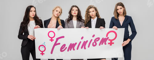 Preview: attractive businesswomen holding large sign with feminism lettering isolated on grey