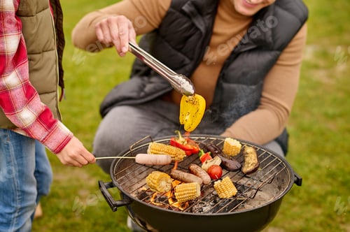 Preview: Man crouched near barbecue with vegetables