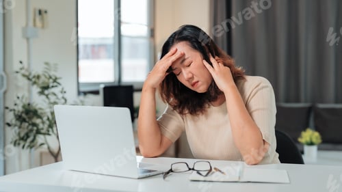Preview: Woman suffering from headache working at laptop