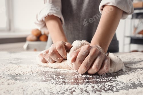 Preview: Woman kneading dough at table in kitchen, closeup