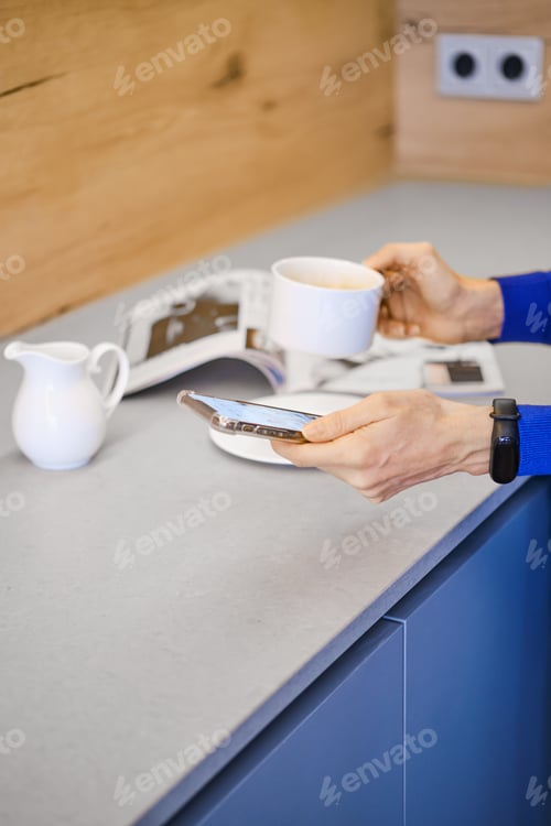 Preview: Hands of woman holding cup of coffee and smartphone