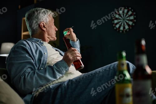 Preview: Elderly Man Playing Darts in Dimly Lit Room