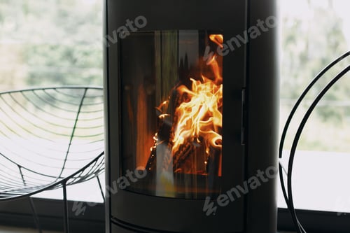 Preview: Modern black fireplace with fire and firewood on metal stand at window with view on mountains