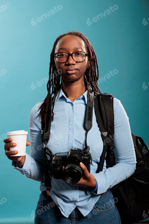 Preview: Young photography entusiast having photo equipment while enjoying beverage on blue background.