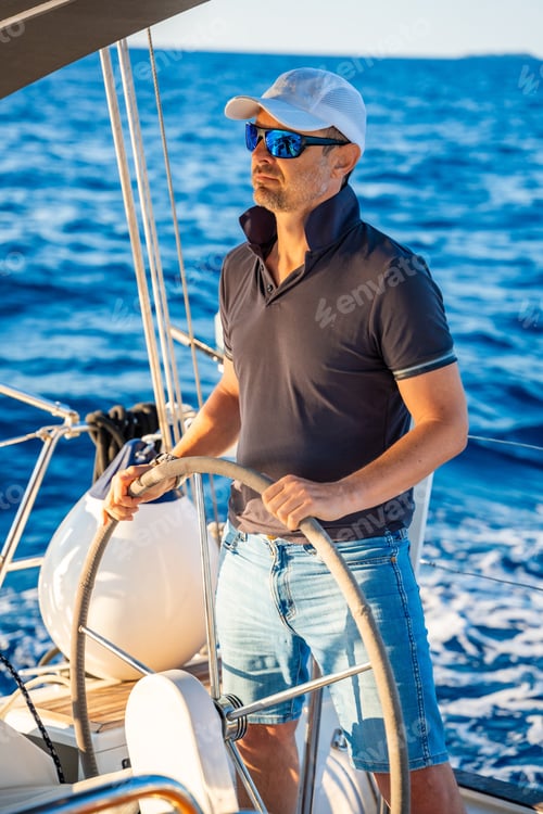 Preview: Young man captain stands at the helm and controls a sailboat during a journey by sea