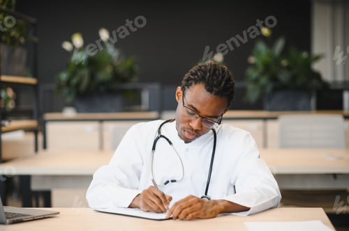Preview: Young male doctor writing at his desk